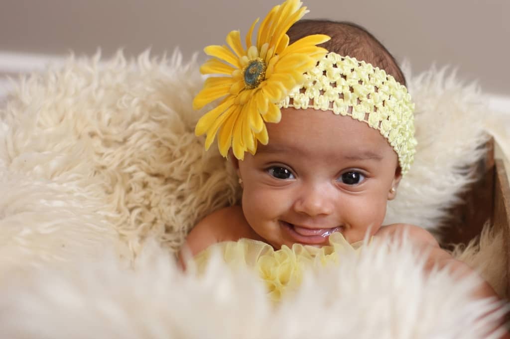 photograph of baby wearing white headband with yellow sunflower